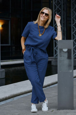 Woman wearing navy blue breathable cotton linen set with short-sleeve top and straight-leg pants outdoors