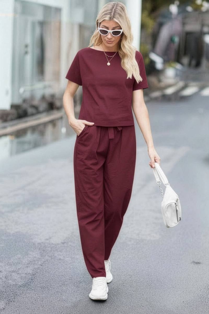 Woman wearing burgundy cotton linen set with short-sleeve top and straight-leg pants walking outdoors