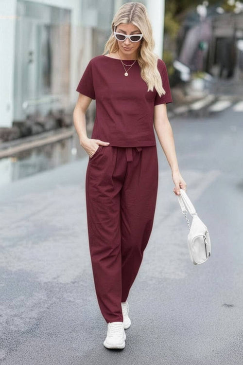 Woman wearing burgundy cotton linen set with short-sleeve top and straight-leg pants walking outdoors