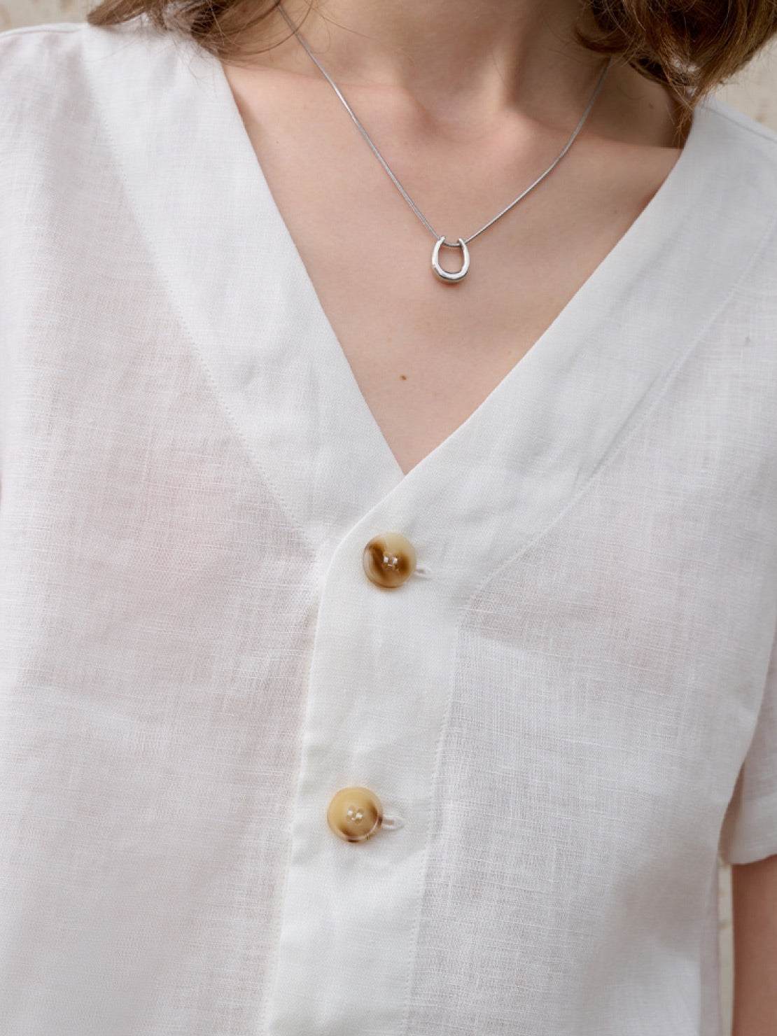 Lightweight 100% linen French top with V-neck, short sleeves, three-button detail, and relaxed boxy cropped hem in light khaki and off white colors