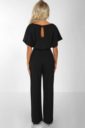 Woman wearing a black chic short-sleeved wide-leg jumpsuit with back keyhole detail and belt.