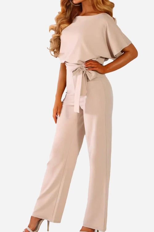 Woman wearing chic short-sleeved wide-leg jumpsuit with belt in light beige color