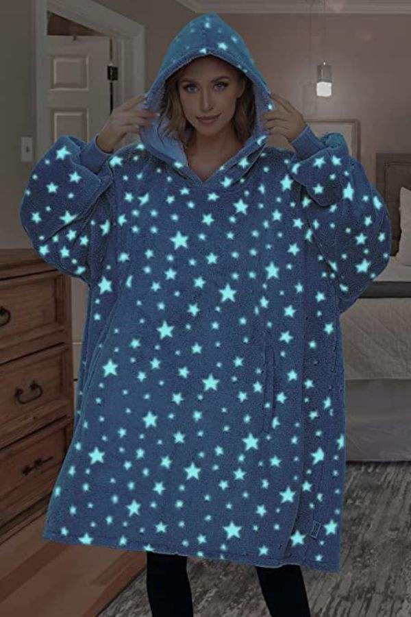Woman wearing oversized Lazy Fleece Blanket Sweater with glow-in-the-dark star pattern and hood indoors