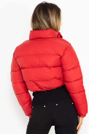 Woman wearing a red cropped puffer jacket with high collar and black pants, back view