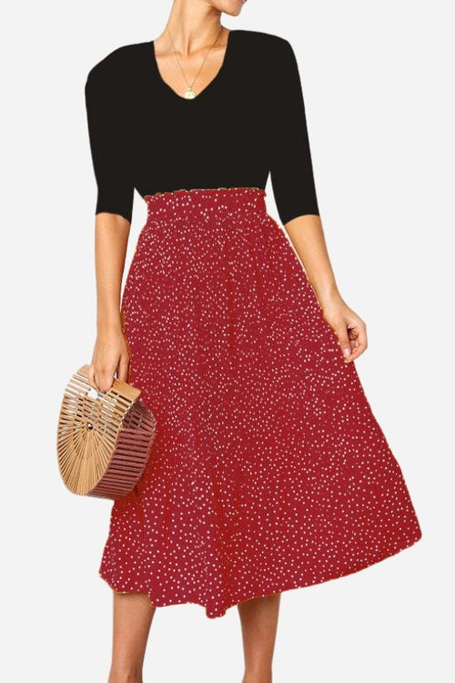 Woman wearing an effortlessly chic polka dot pleated midi skirt with a black top and wooden handbag
