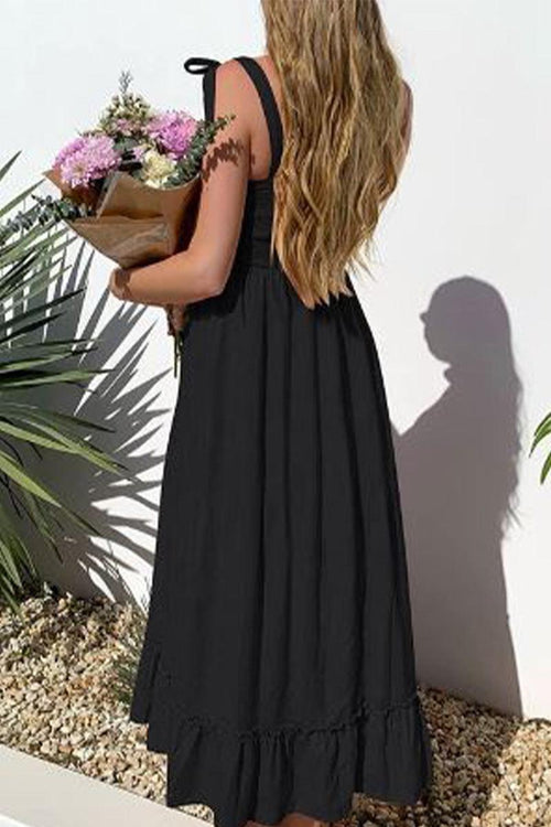 Woman wearing black Sunkissed Spaghetti Boho Dress with adjustable straps holding flowers outdoors