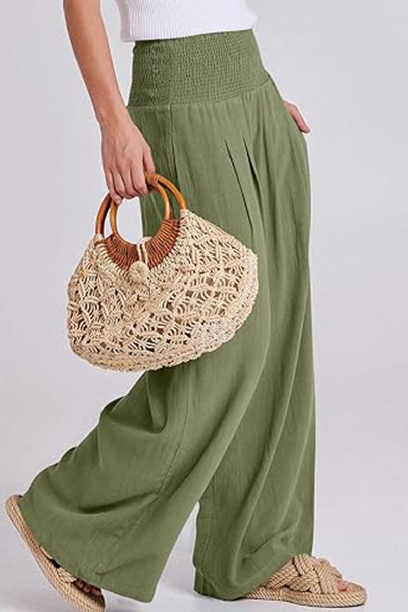 Green palazzo pants with smocked waistband paired with woven handbag and sandals.