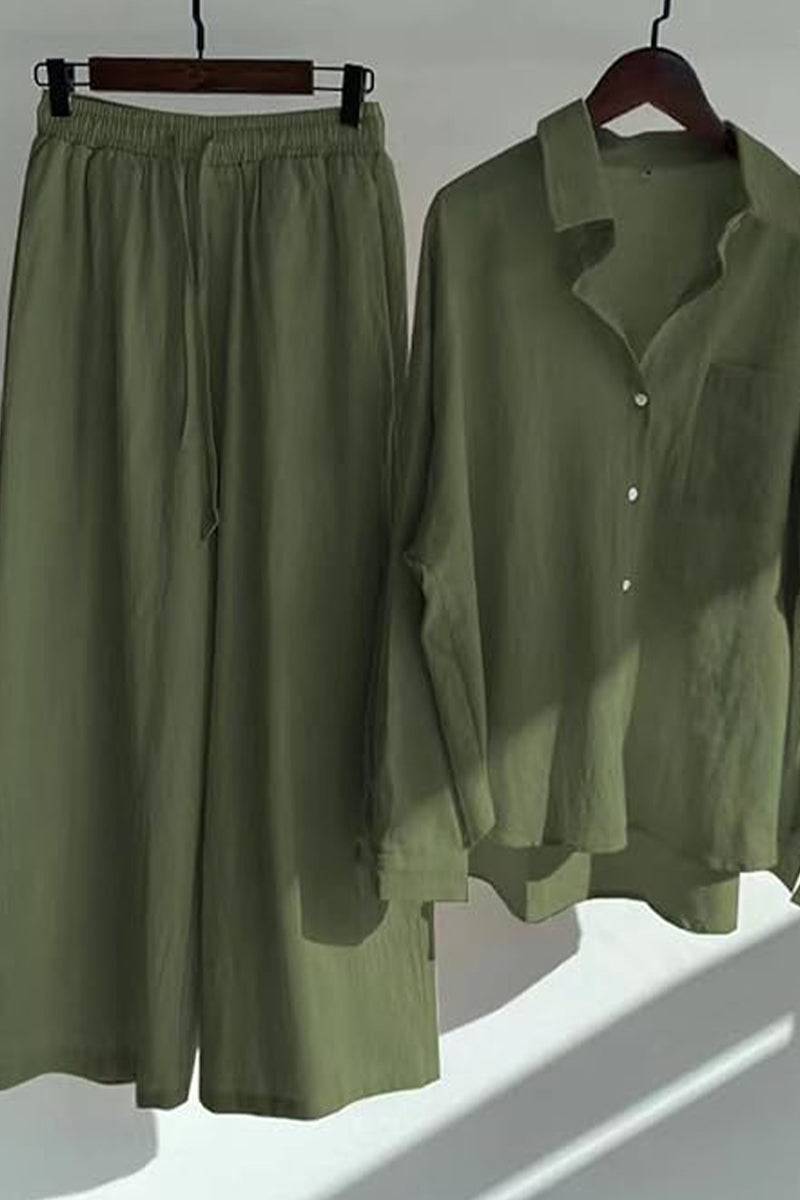Olive green oversized shirt and palazzo pants two-piece linen set hanging on wooden hangers with natural light shadows