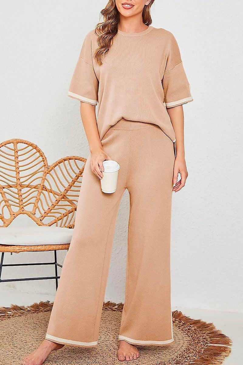 woman wearing beige short sleeved relaxed fit lounge two-piece set with wide leg pants holding a white cup standing indoors