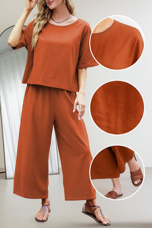 Woman wearing rust-colored loose fit co-ord set with wide-leg pants and short sleeve top, showcasing fabric texture and relaxed fit details.