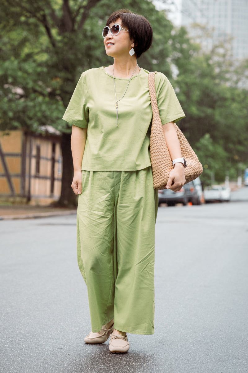 Woman wearing loose fit co-ord set in light green with wide-leg pants and short-sleeve top outdoors.