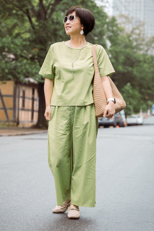 Woman wearing loose fit co-ord set in light green with wide-leg pants and short-sleeve top outdoors.