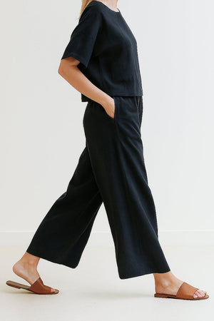 Black loose fit co-ord set with wide-leg trousers and relaxed short-sleeve top, styled with sandals.