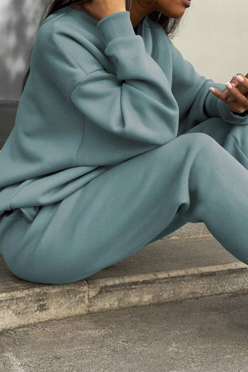Woman wearing a comfortable cotton-blended two-piece tracksuit in muted blue-gray color sitting outdoors.