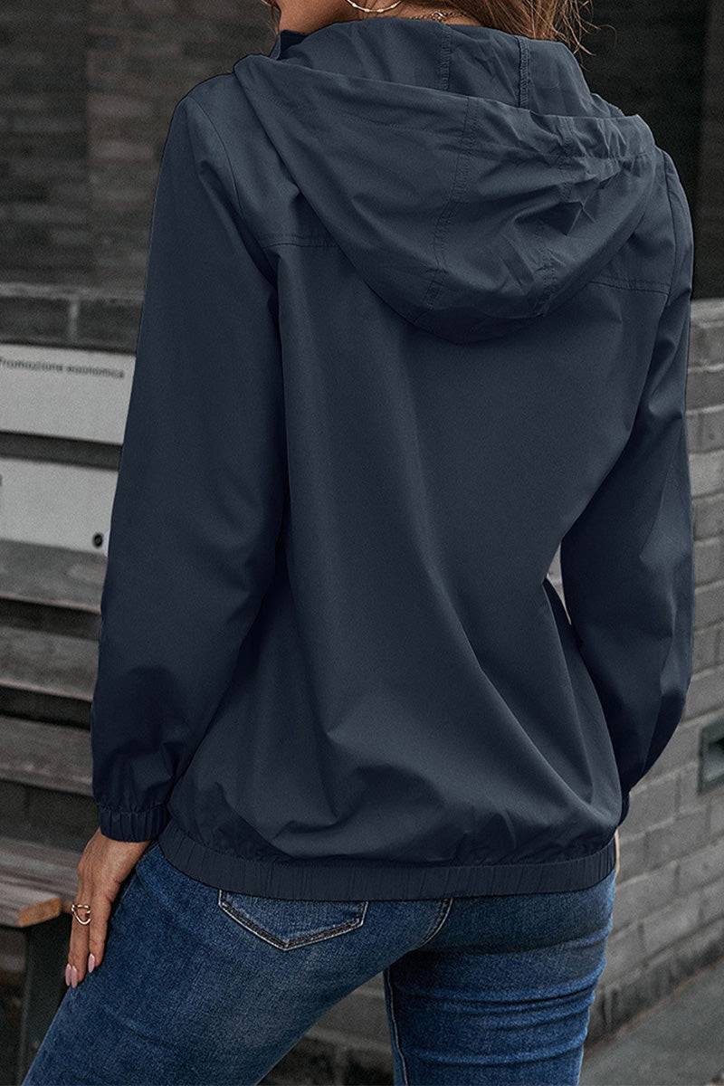 Woman wearing a navy blue outdoor hooded raincoat and windbreaker from the back