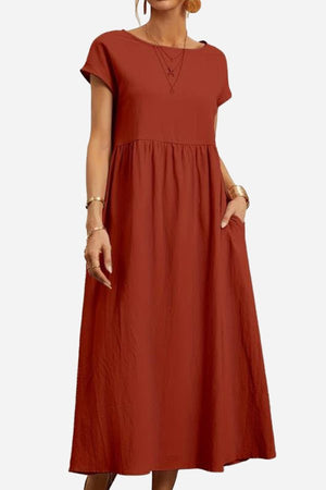 Women’s capped-sleeve voluminous pleated midi dress in rust with a stomach-flattening drape and pockets.