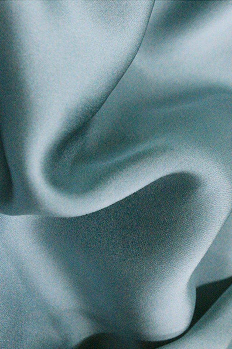 Close-up of smooth light blue 100% mulberry silk fabric with soft folds and sheen