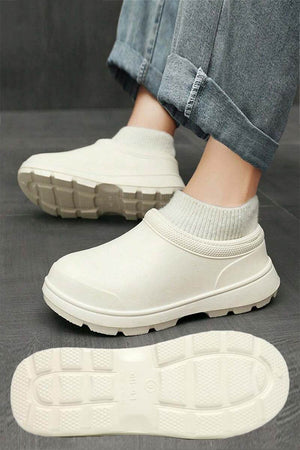 White fleece-lined comfort clogs with waterproof exterior and textured grip sole worn with rolled-up jeans