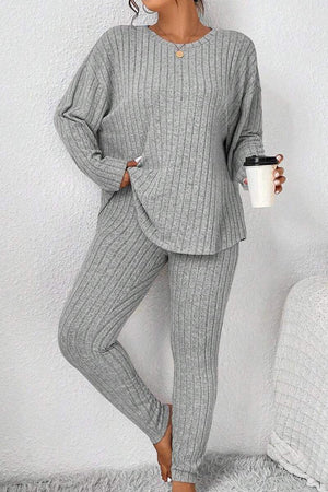 Woman wearing a gray Body Confident Oversized Knit two-piece set holding a coffee cup against a white wall background