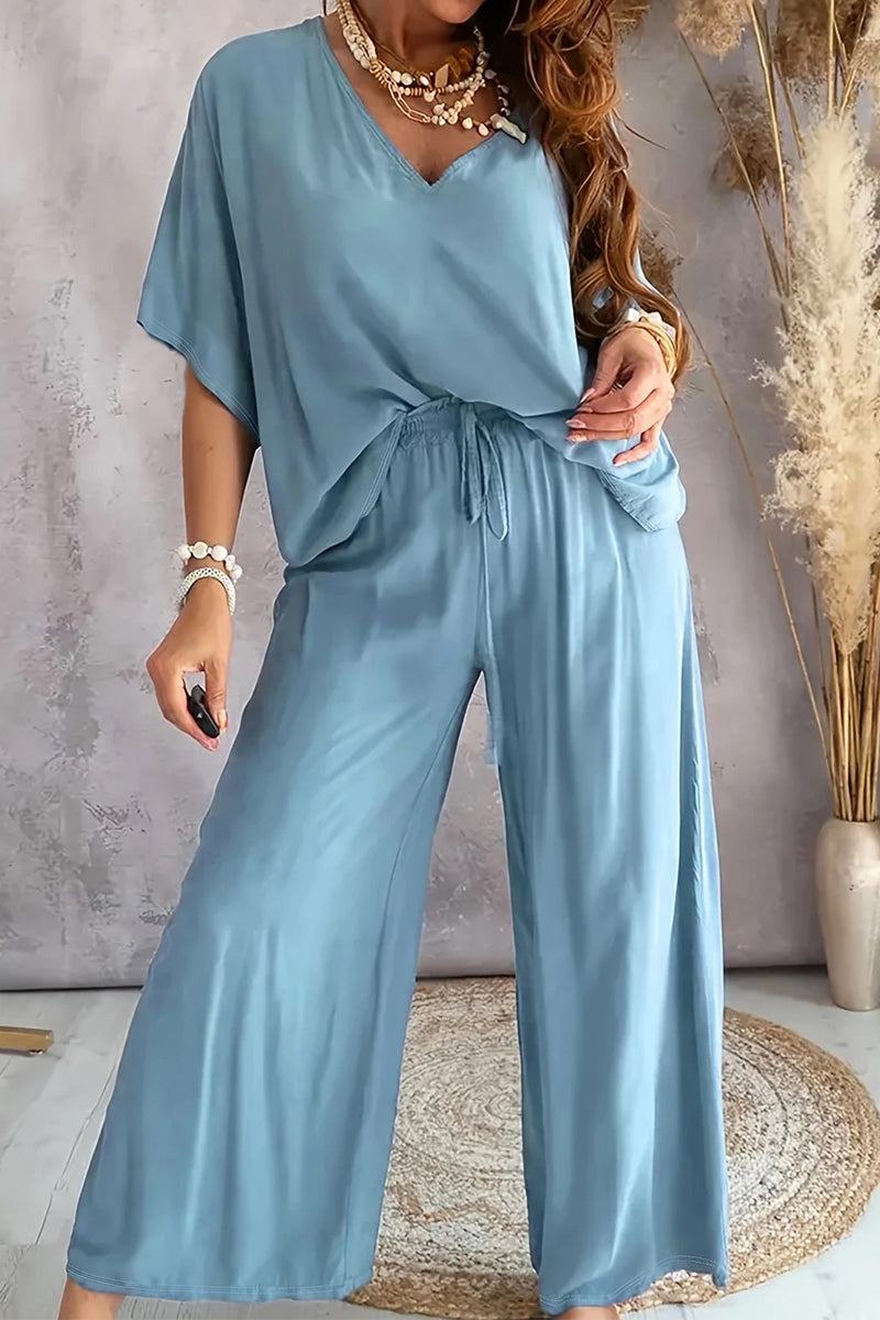 Light blue elegant two-piece pantsuit with V-neck top and wide-leg pants, styled with jewelry.