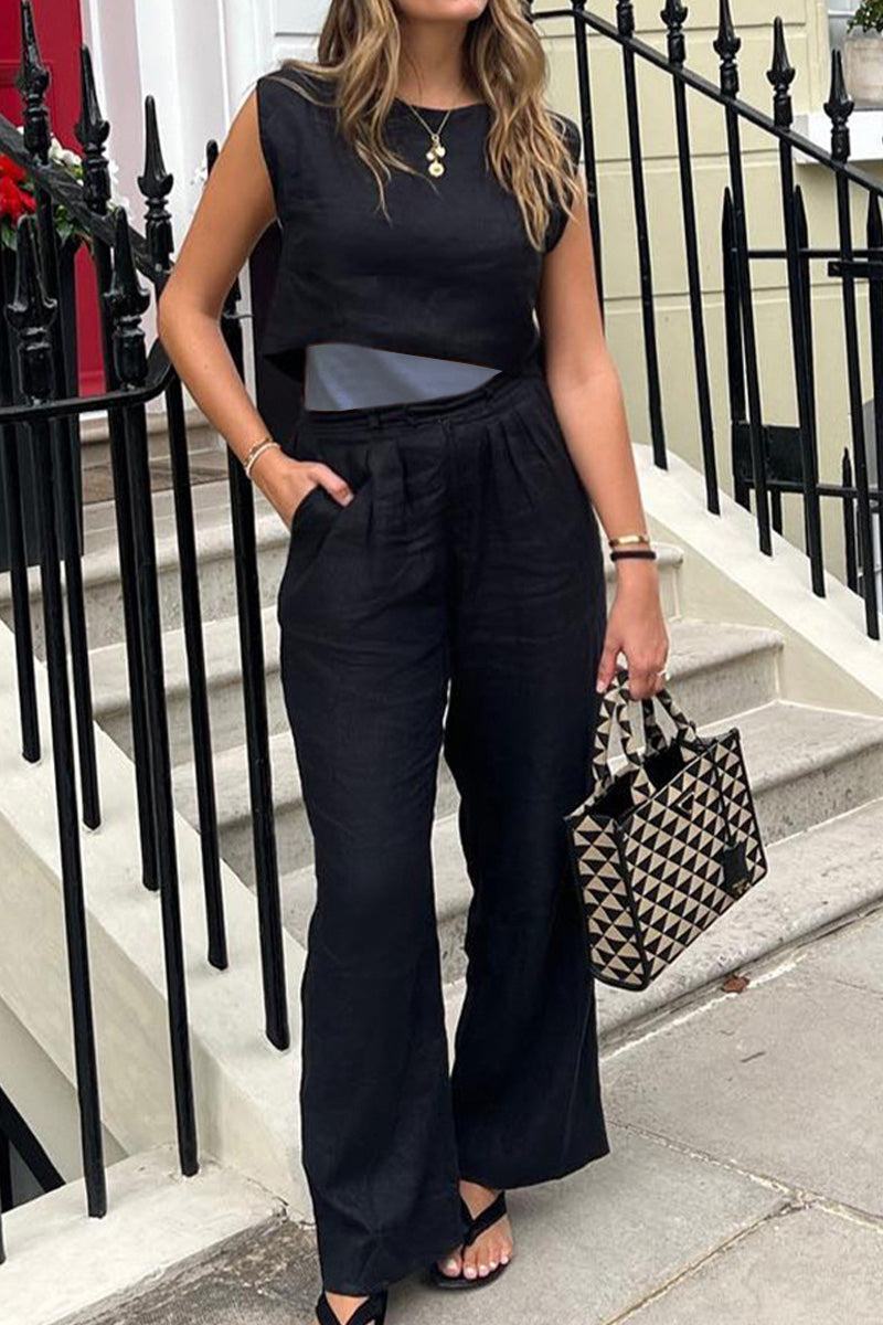 Woman wearing black cotton-linen blend sleeveless crop top and wide-leg pants holding a geometric patterned handbag outdoors