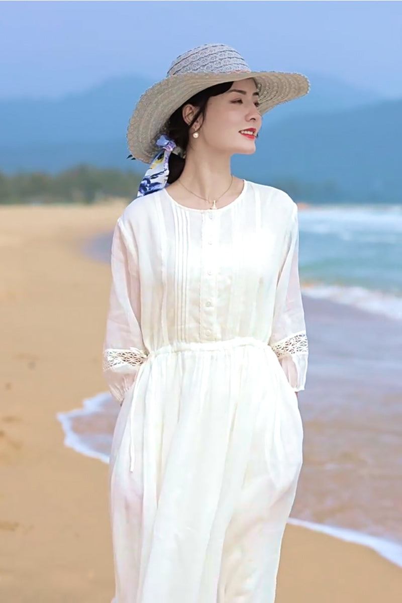 woman wearing white 100 linen coastal shift dress and straw hat on beach