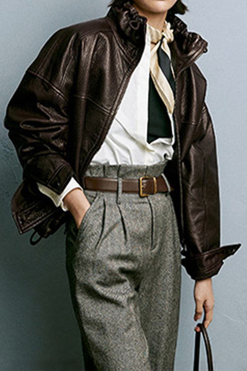Woman wearing a dark brown genuine sheepskin leather jacket with ruffled collar and gray high-waisted pants.