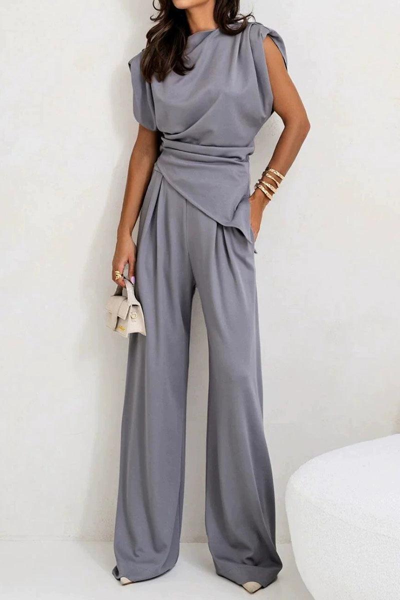 Woman wearing Manhattan Lines Draped two-piece gray set with asymmetrical draped sleeveless top and wide-leg pants.