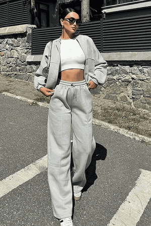 Woman wearing The Voyager Zip Set light gray zip-front sweatshirt and wide-leg joggers with pockets outdoors