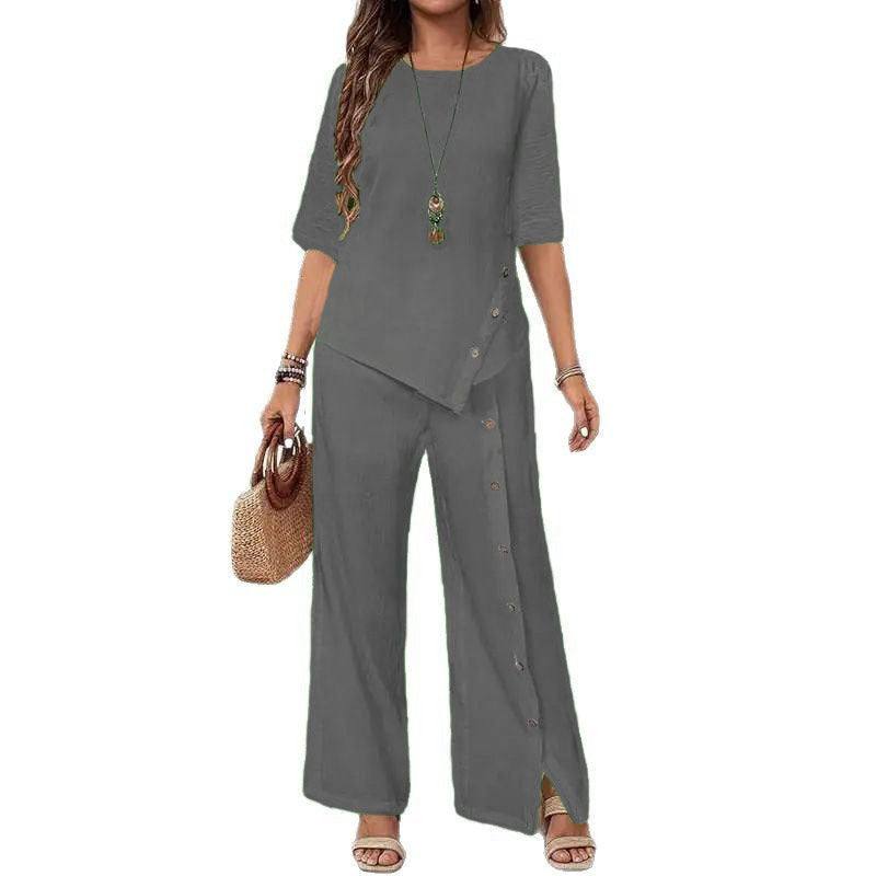 Woman wearing gray Asymmetry Flow Co-ord set with button-front top featuring asymmetrical hem and loose flowing pants, accessorized with necklace and handbag