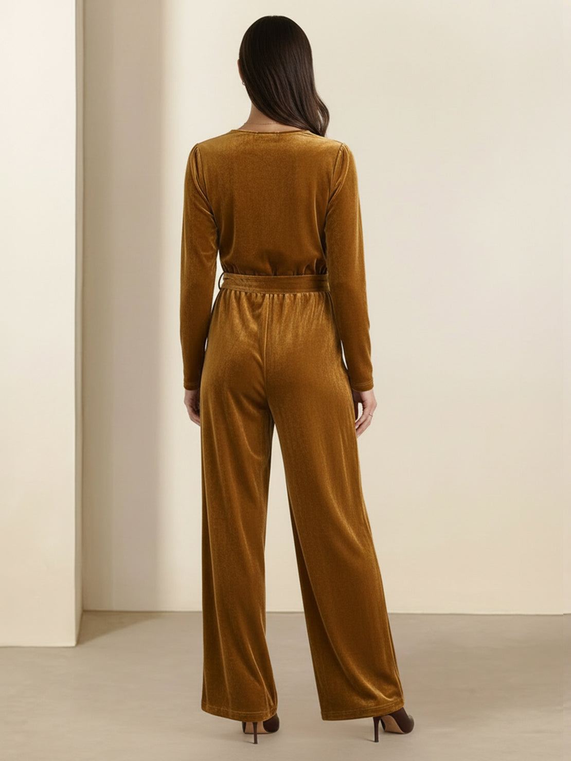 Woman wearing a deep V-neck velvet suit with long sleeves, removable waist tie, and wide-leg pants with side pockets