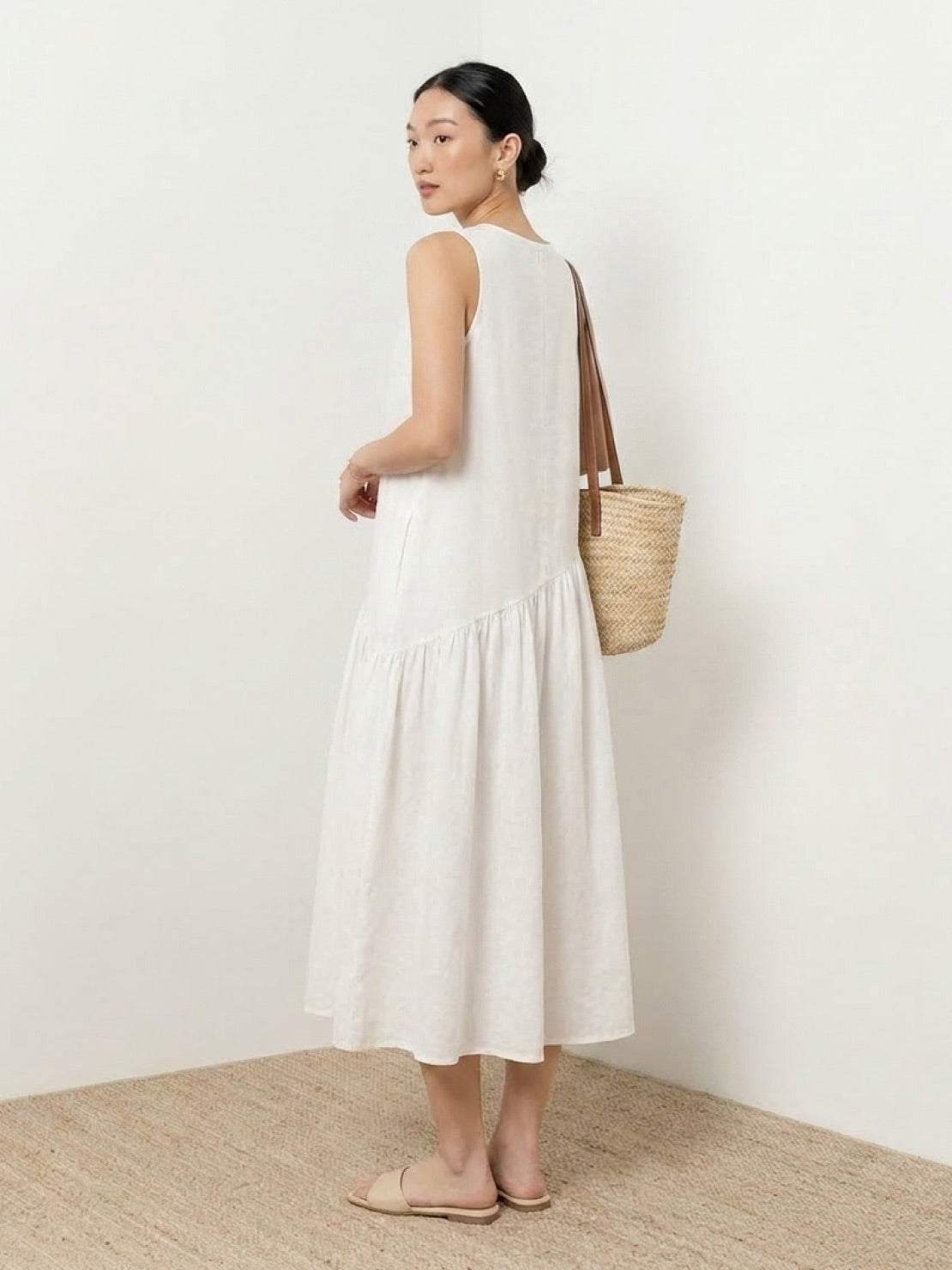 Woman wearing a cotton-linen summer midi dress with a tiered skirt and relaxed drop-waist silhouette in natural fabric