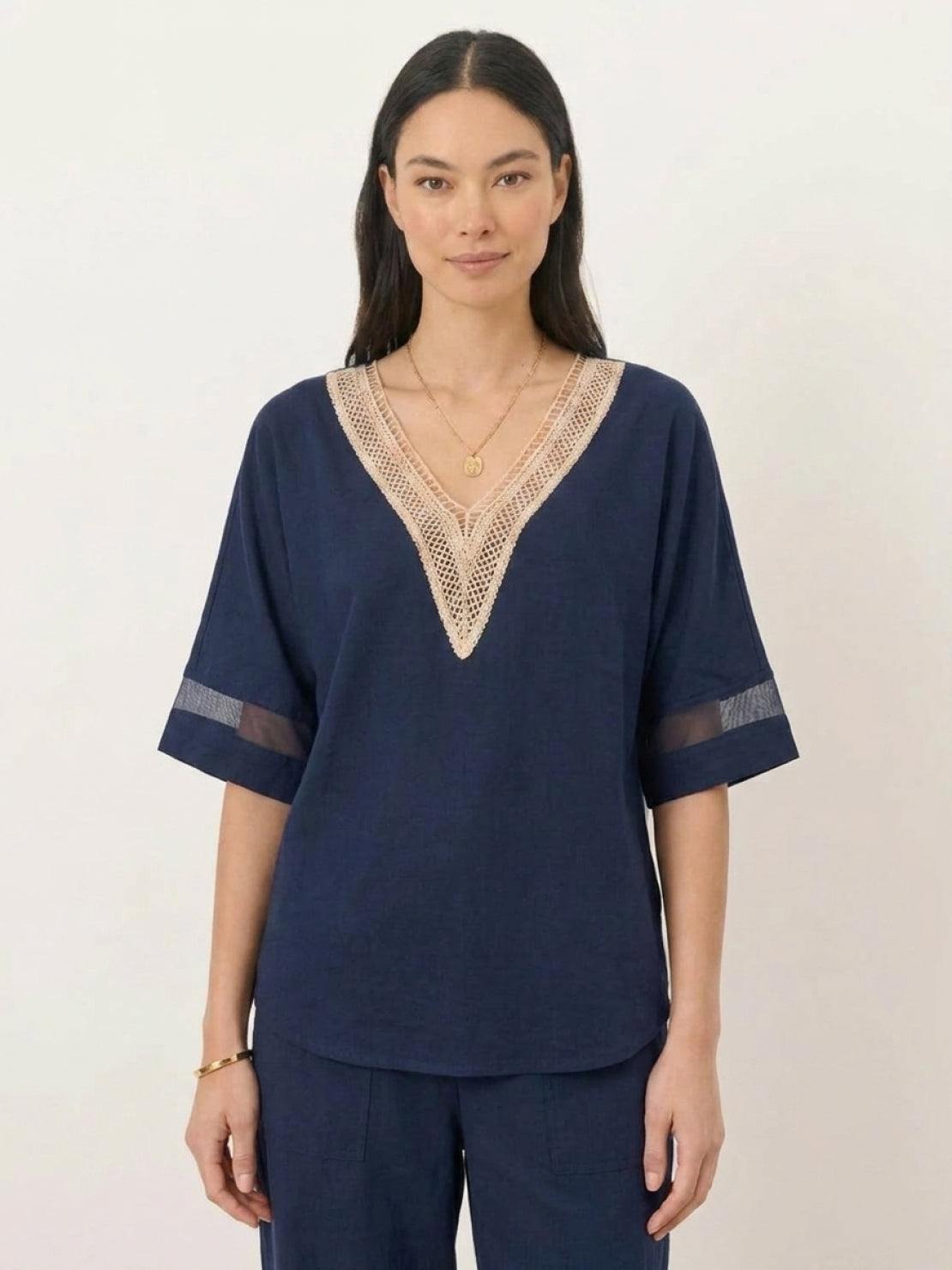 Mature woman wearing a lightweight linen top with V-neck and button details in a relaxed boxy shape