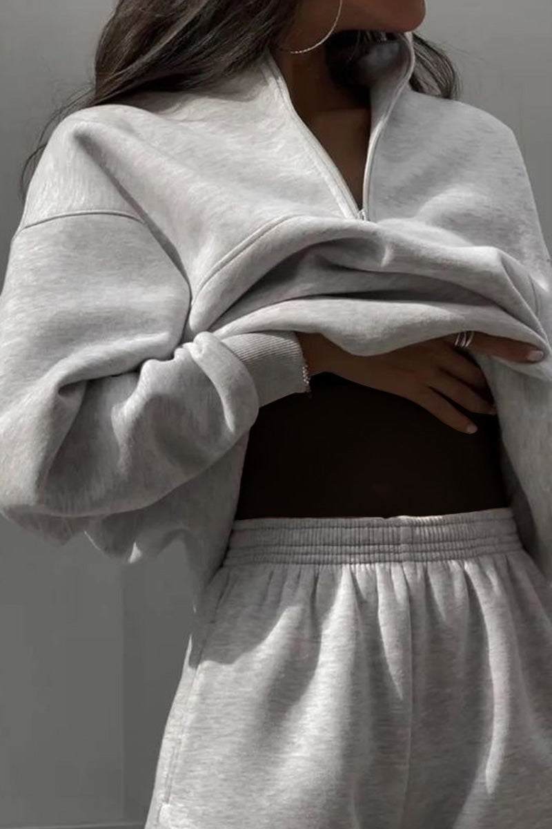 Woman wearing a comfortable cotton-blended two-piece tracksuit with high collar and deep zipper in monochrome design