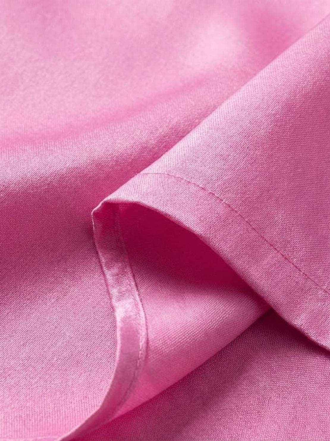 Close-up of soft pink asymmetrical two-piece trouser set fabric with silky texture