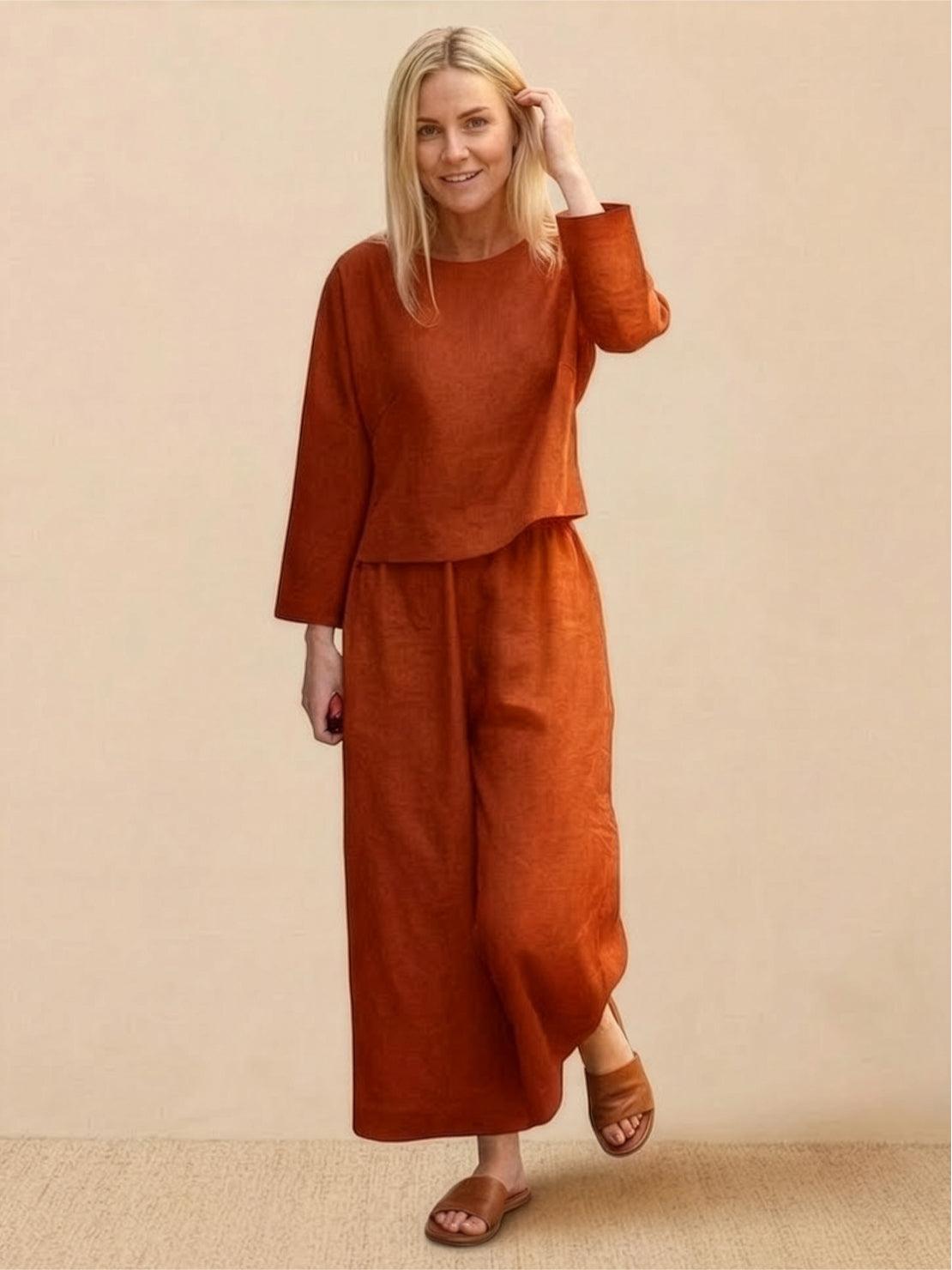woman wearing loose solid color rust orange two-piece set with long sleeves and wide-leg pants