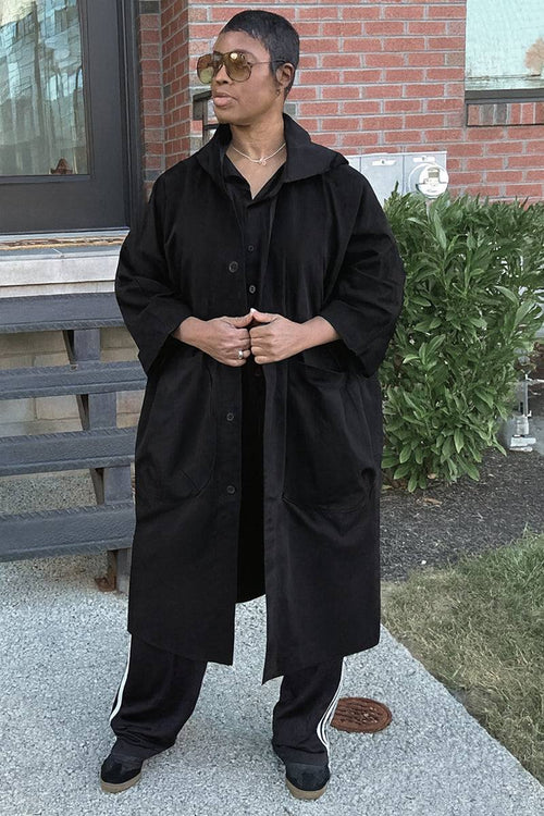 Oversized black water-resistant windbreaker jacket with snap-button closure and large pockets