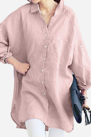 Pink oversized linen shirt with long sleeves and front pocket, styled casually with rolled-up sleeves and white pants.