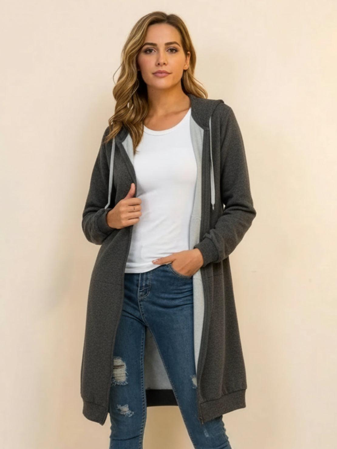 Woman wearing oversized long zip sweatshirt hoodie in dark gray with front pockets and drawstring hood