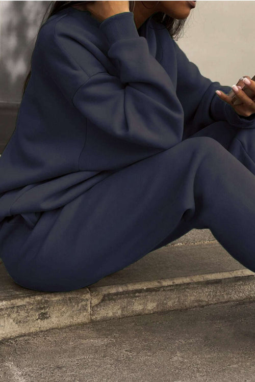 Close-up of woman wearing navy cotton blend tracksuit sitting outdoors