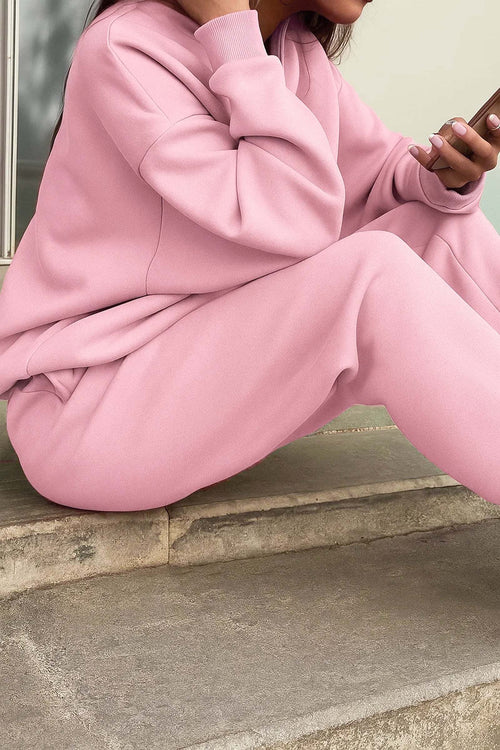 woman wearing soft pink cotton blend tracksuit sitting outdoors using smartphone