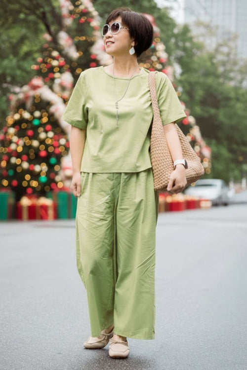 Woman wearing light green loose fit co-ord set with short sleeves and wide-leg pants outdoors near Christmas decorations
