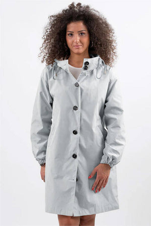 Woman wearing light gray Rain Couture Windbreaker oversized water-resistant jacket with hood and buttons.