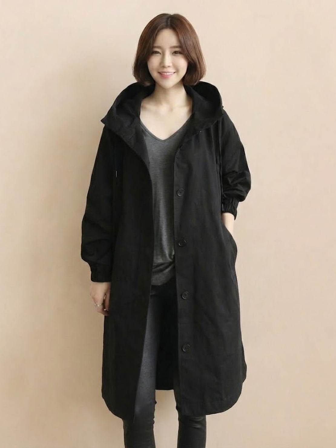 Woman wearing black oversized Rain Couture Windbreaker water-resistant jacket with hood and button closure