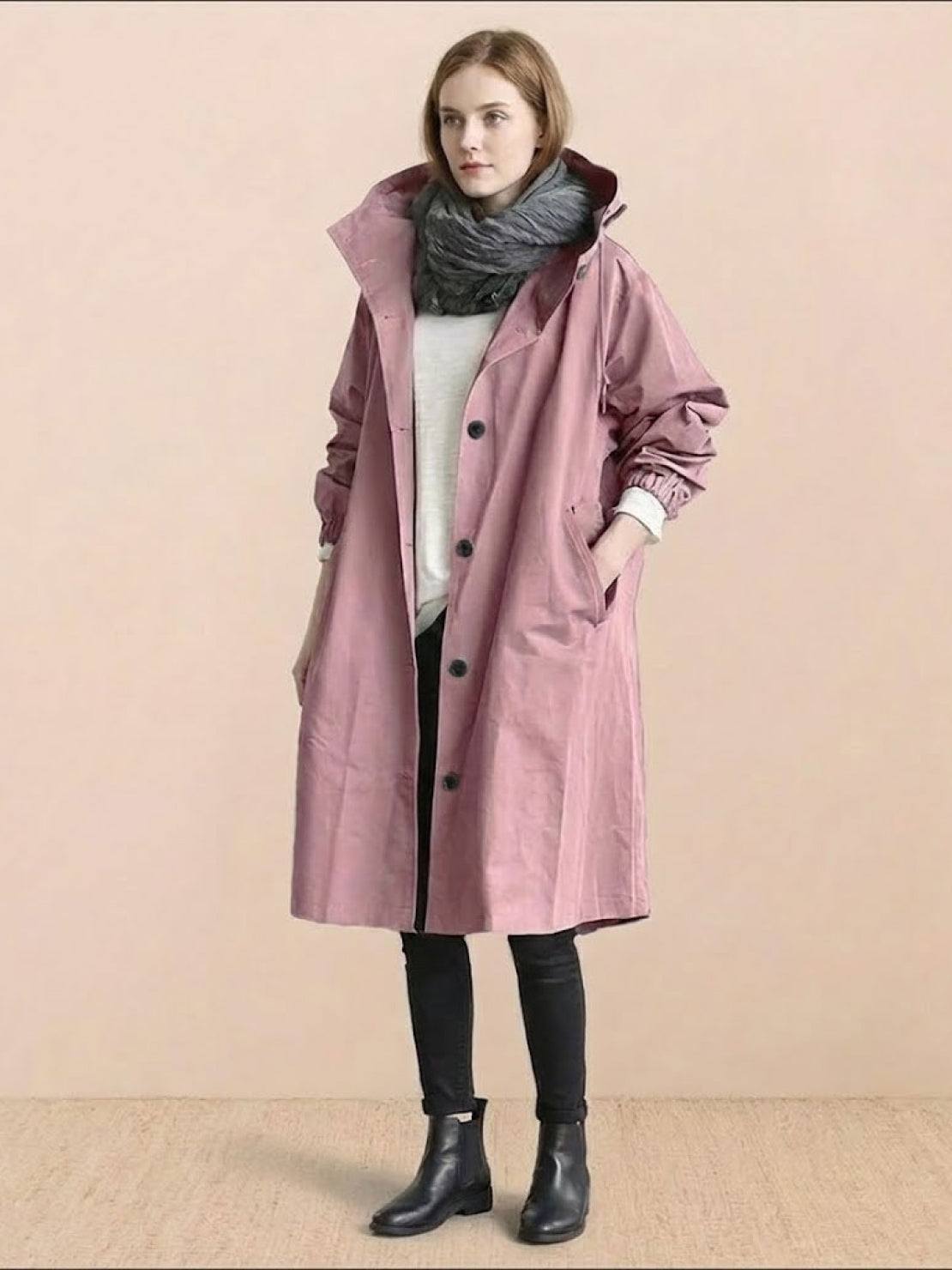 Woman wearing oversized pink Rain Couture Windbreaker with scarf, black leggings, and boots against beige background