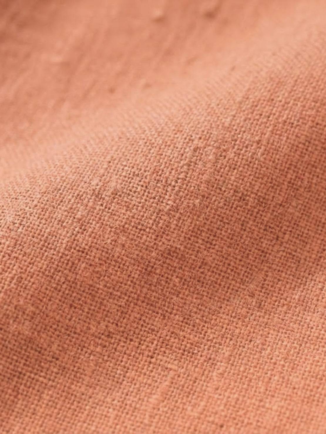 Close-up of soft peach-colored cotton fabric texture for lightweight cotton dress