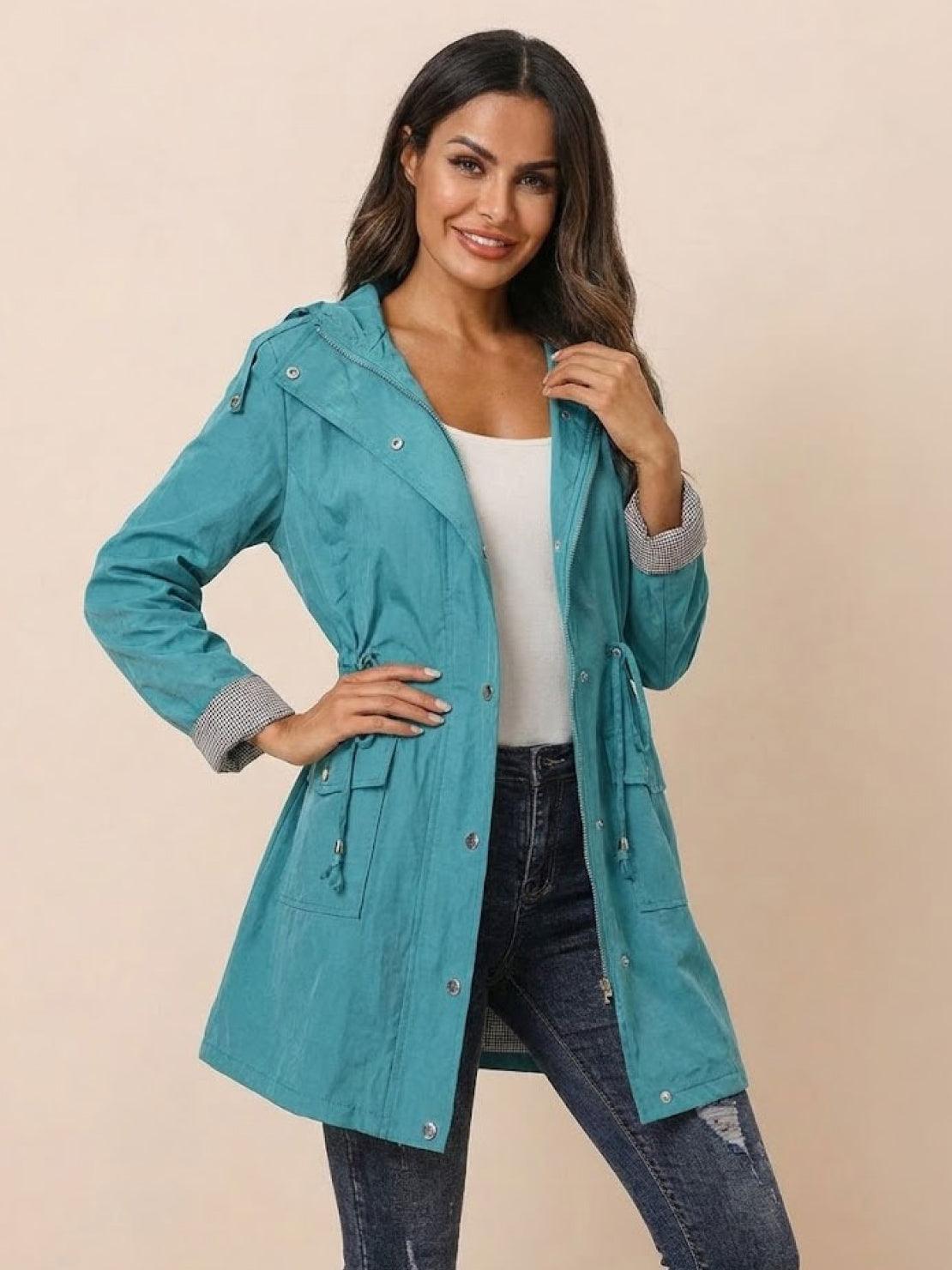 woman wearing teal water resistant windbreaker jacket with hood and striped cuffs