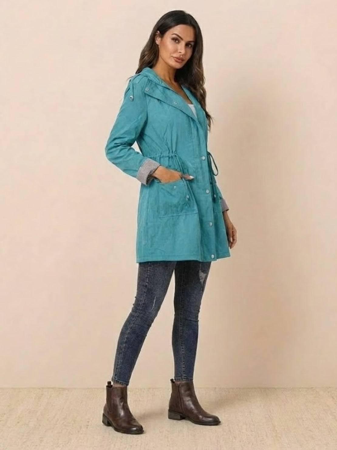 Woman wearing teal water resistant windbreaker rain jacket with hood and striped details