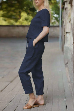 Woman wearing navy blue cotton linen set with relaxed short-sleeve top and straight-leg pants outdoors