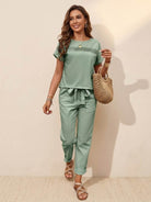 woman wearing light green 100% cotton total comfort two-piece set with short sleeves and pants holding straw bag